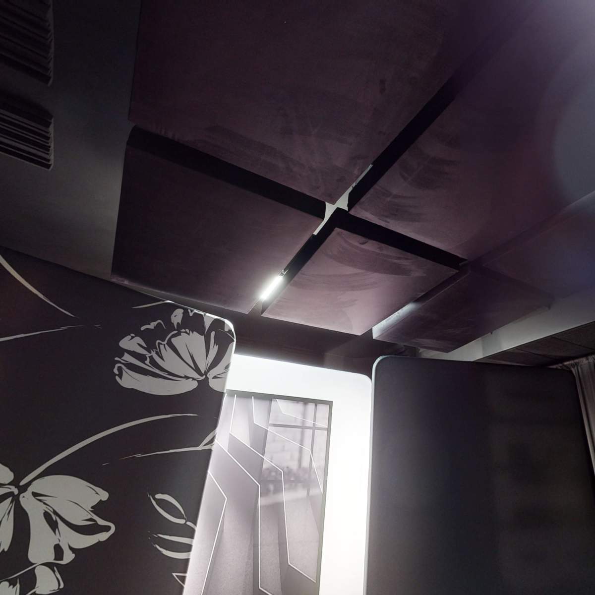 A room interior with padded acoustic panels on the ceiling and large fabric partitions on the sides.
