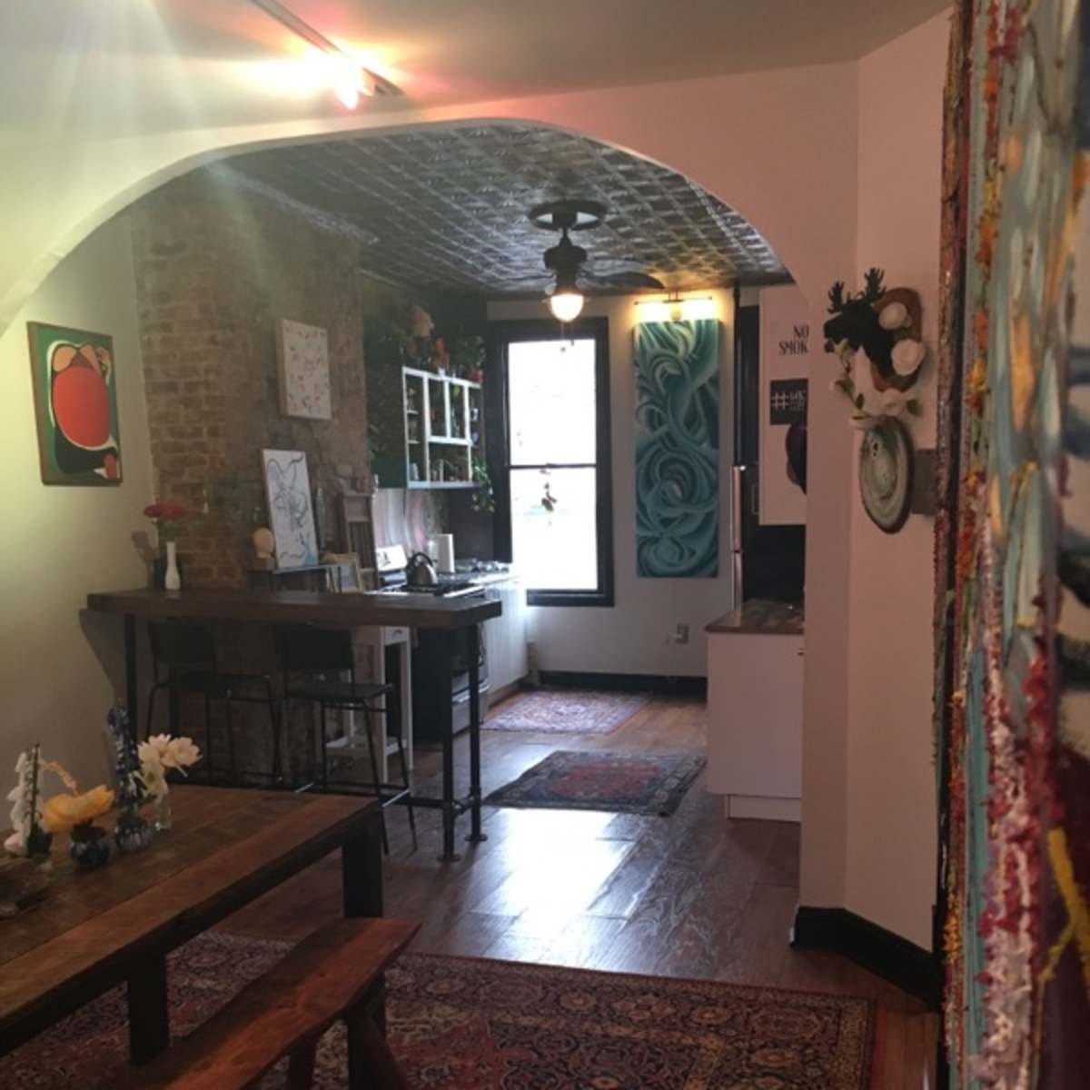A cozy kitchen and dining area with wooden furniture, brick walls, and patterned rugs.