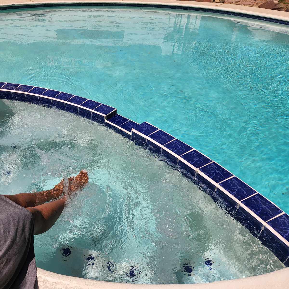A person relaxes with their feet submerged in the clear water of a spa pool.
