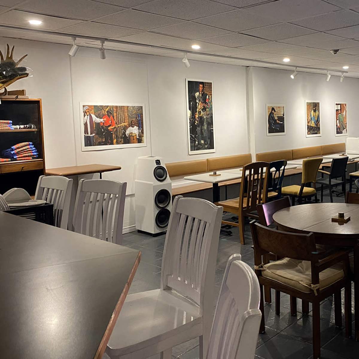 A spacious café interior with a mix of tables and chairs, featuring artwork on the walls and a counter in the foreground.