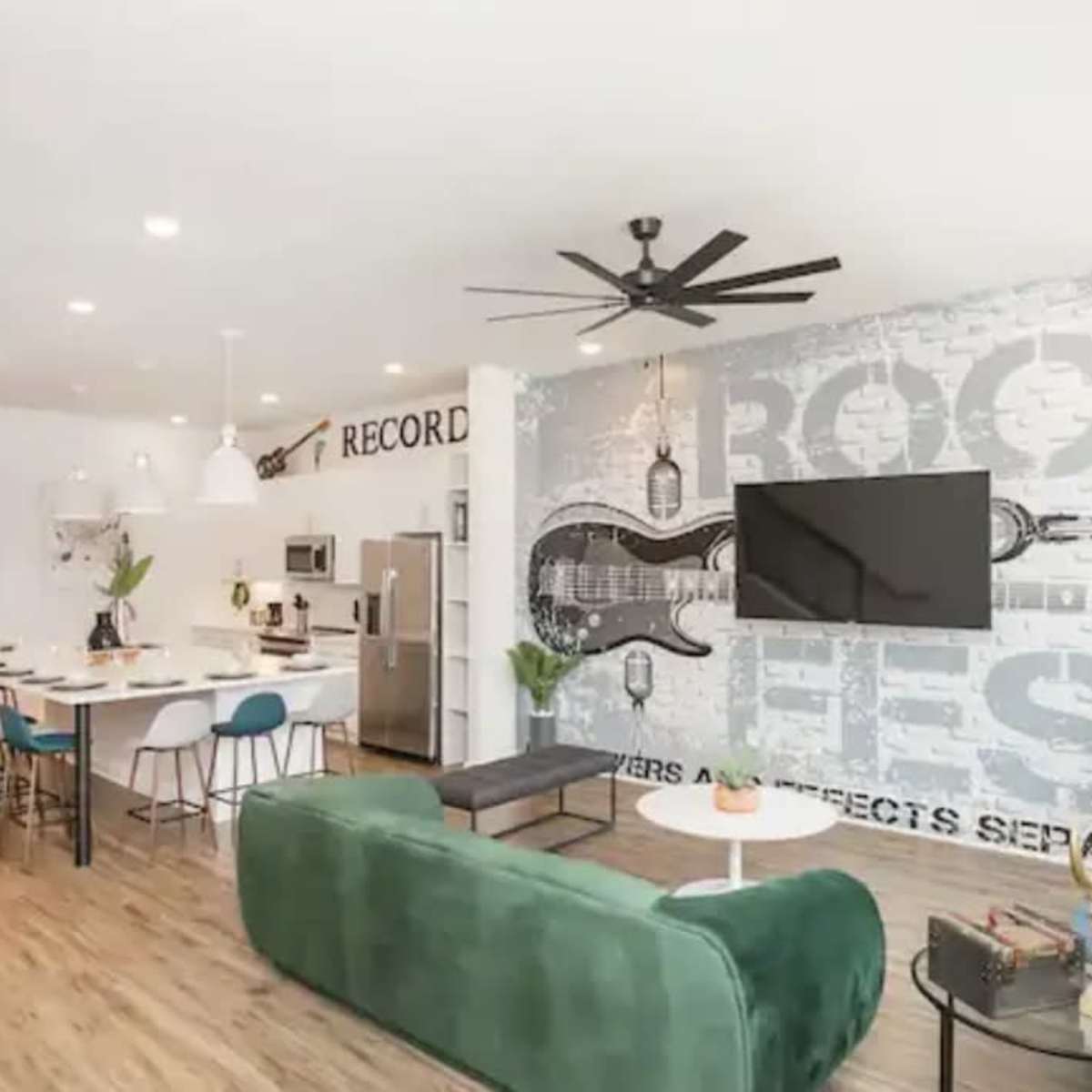 A modern living space with a kitchen area, dining table, and a large wall mural featuring musical elements, complemented by stylish furniture and plants.