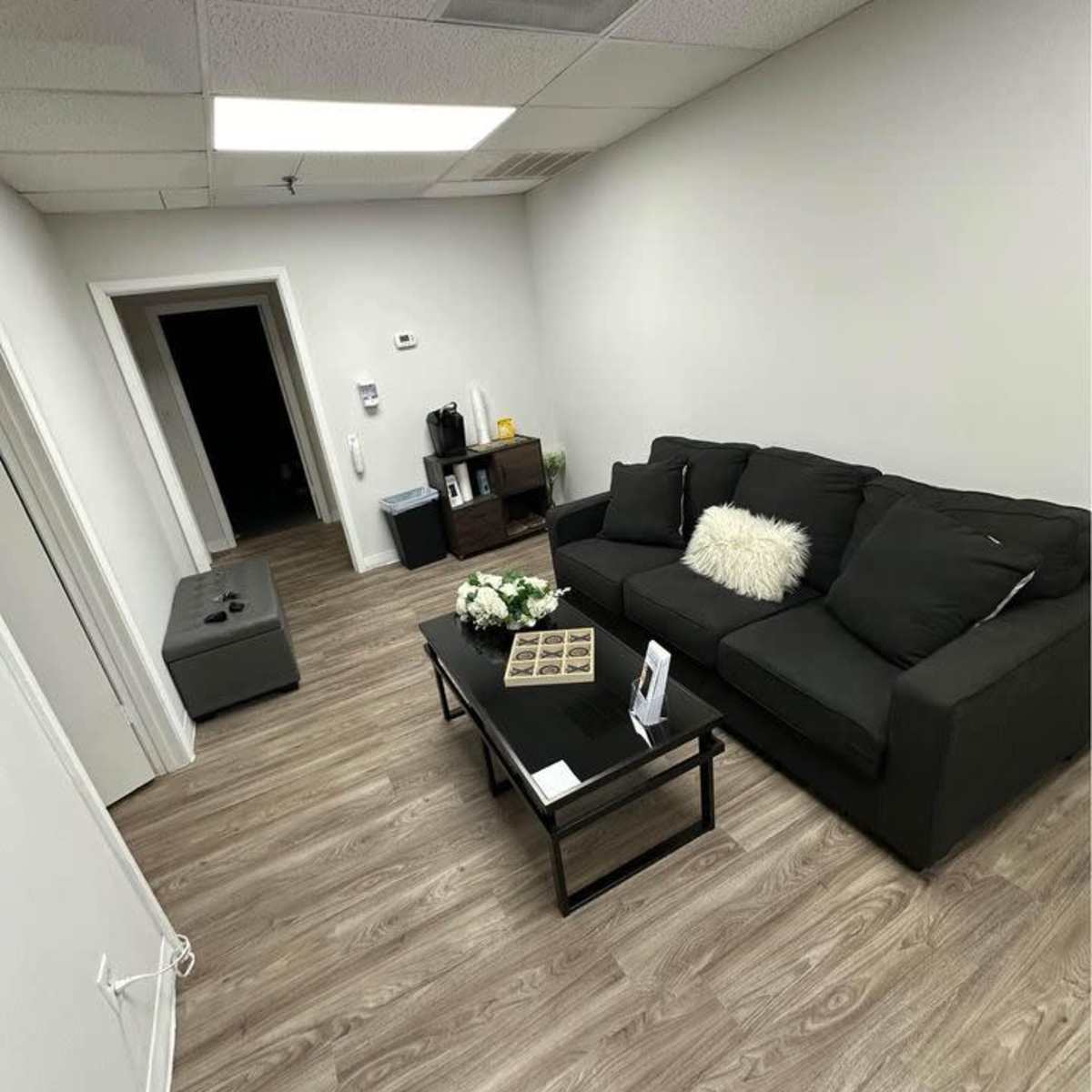 A small waiting area with a dark sofa, a coffee table, and a decorative arrangement of flowers.