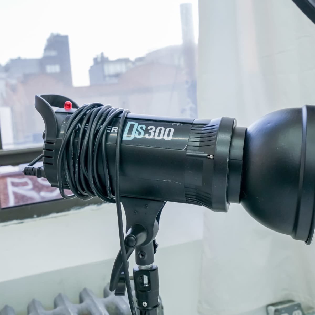 A photography studio lighting fixture is mounted on a stand near a window.