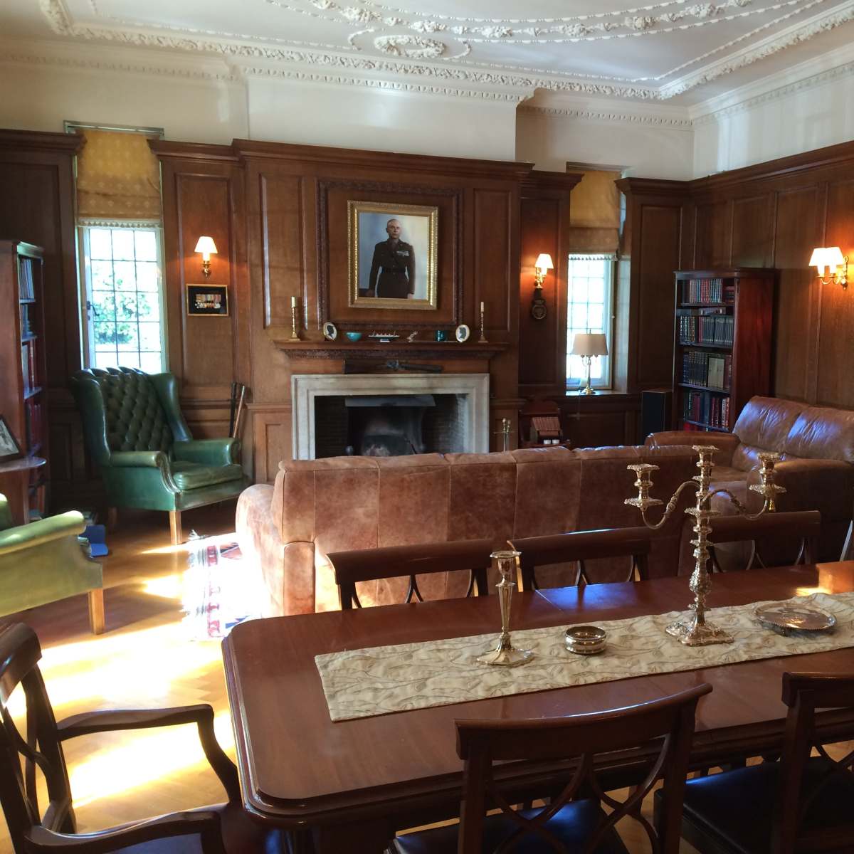 A richly decorated room with wooden paneling, a dining table at the center, a fireplace, and various pieces of vintage furniture.