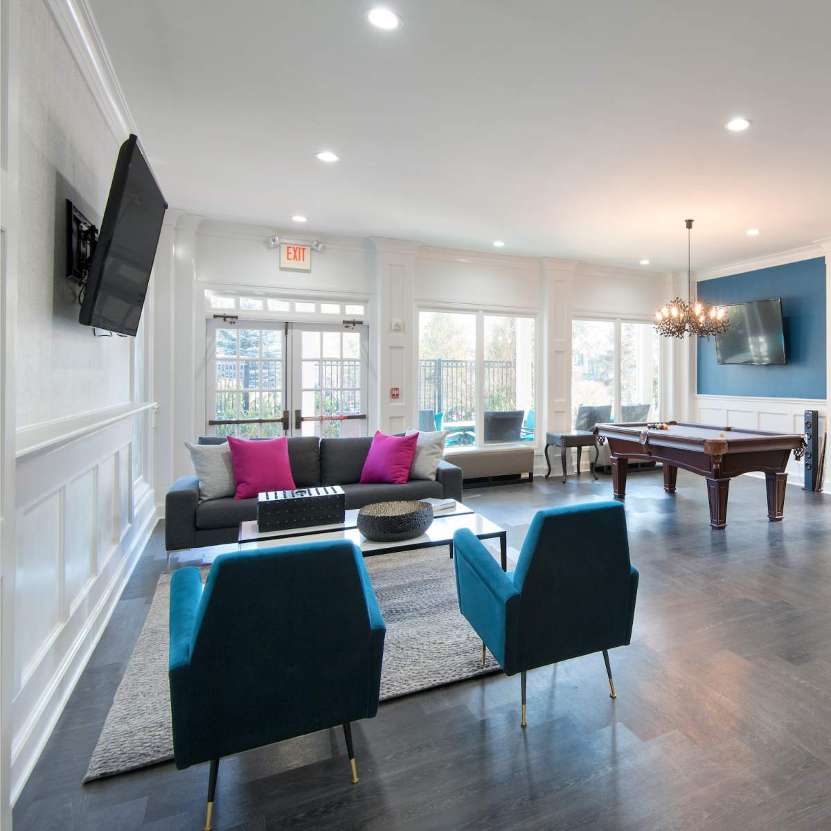 A modern lounge area with a pool table, comfortable seating, a large television, and a stylish bar counter.