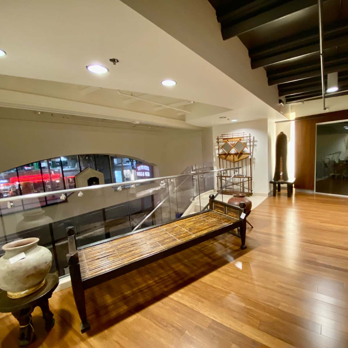 A modern interior space with wooden floors, a decorative bench, and various art pieces displayed on shelves.