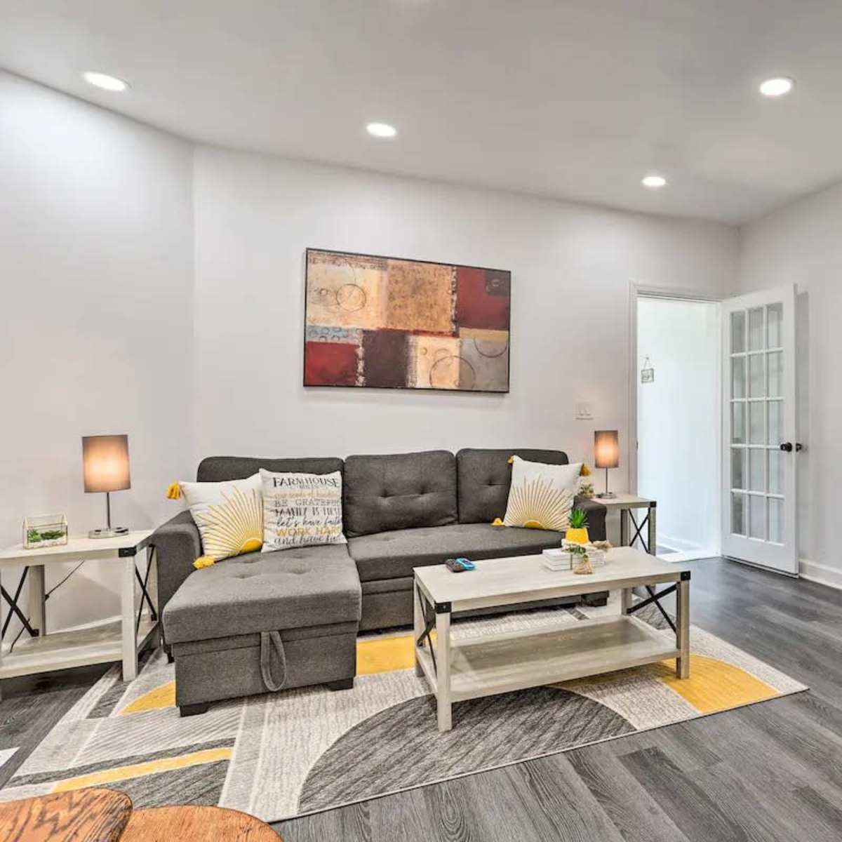 A modern living room features a gray sofa, a coffee table, and a television mounted on a white cabinet against a light-colored wall.