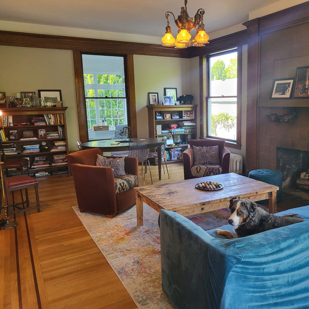 A cozy living room with a blue sofa, a wooden coffee table, a fireplace, and shelves filled with books.