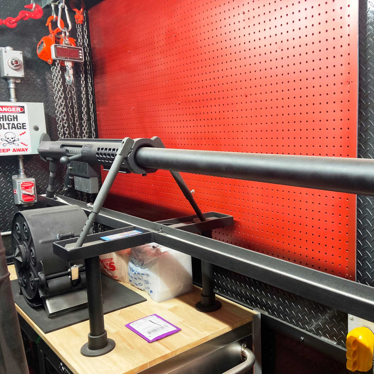 A black firearm mounted on a display stand against a patterned red wall.