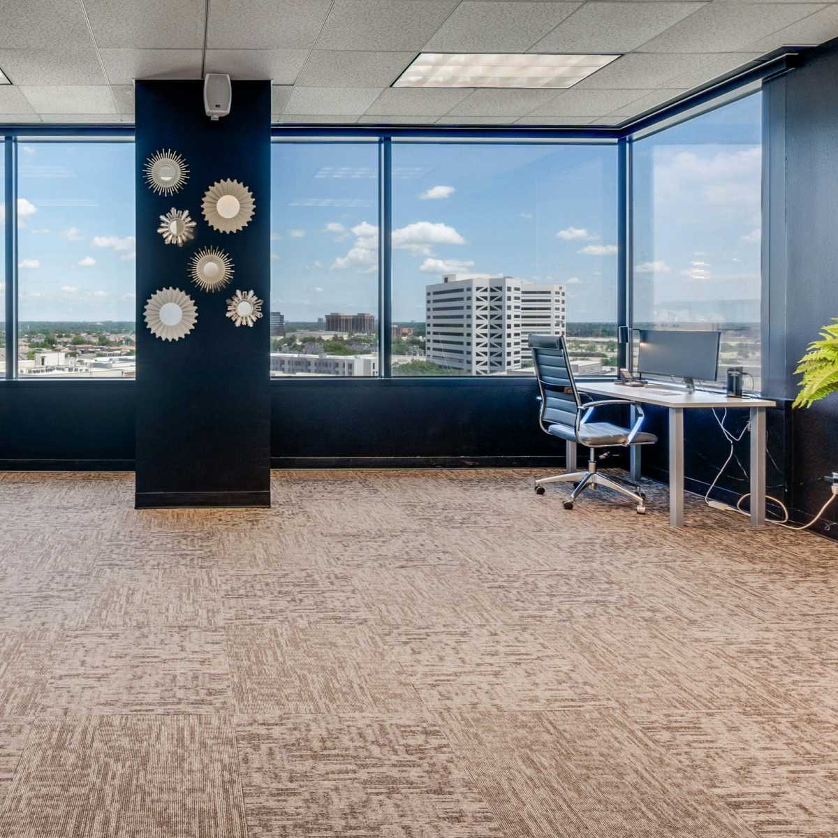 A modern office space with two desks facing large windows that offer a view of a city landscape.