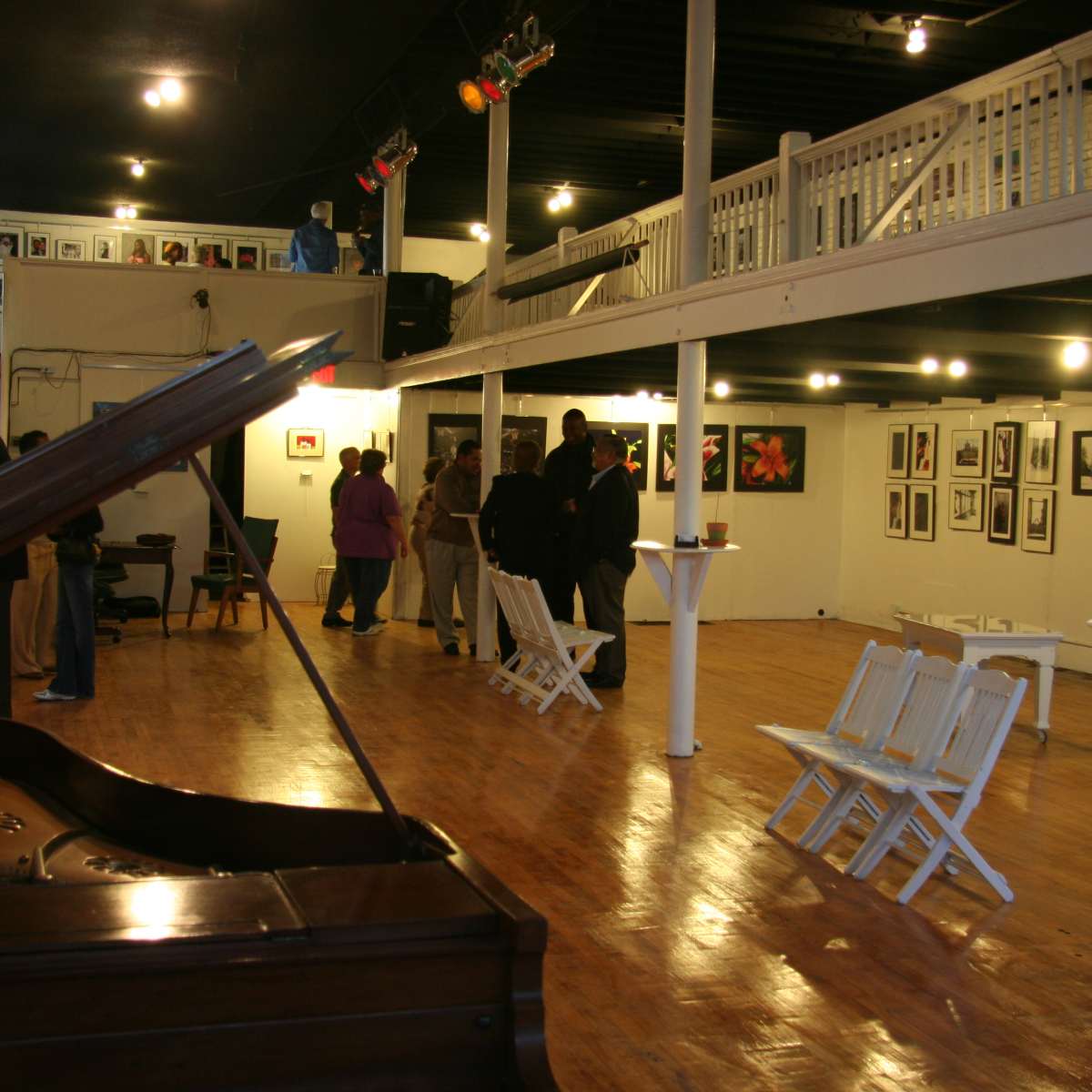 An art gallery with a grand piano in the foreground and visitors engaging with the displayed photographs on the walls.