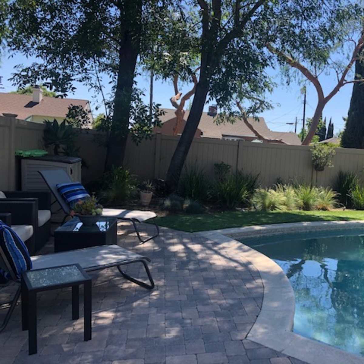 A backyard with a swimming pool surrounded by lounge chairs and landscaped greenery.