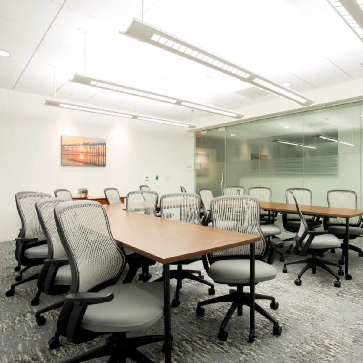 A modern conference room with several tables and ergonomic chairs arranged around a spacious layout.