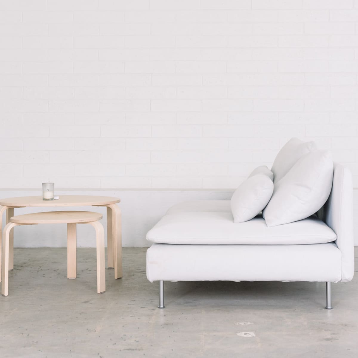 A minimalist living space with a white sofa and a light wooden side table.