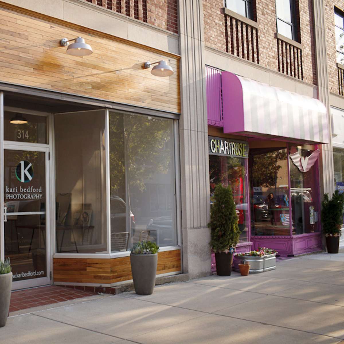 A storefront for "Kari Bedford Photography" with large glass windows next to a vibrant pink shop labeled "CALATRICE."