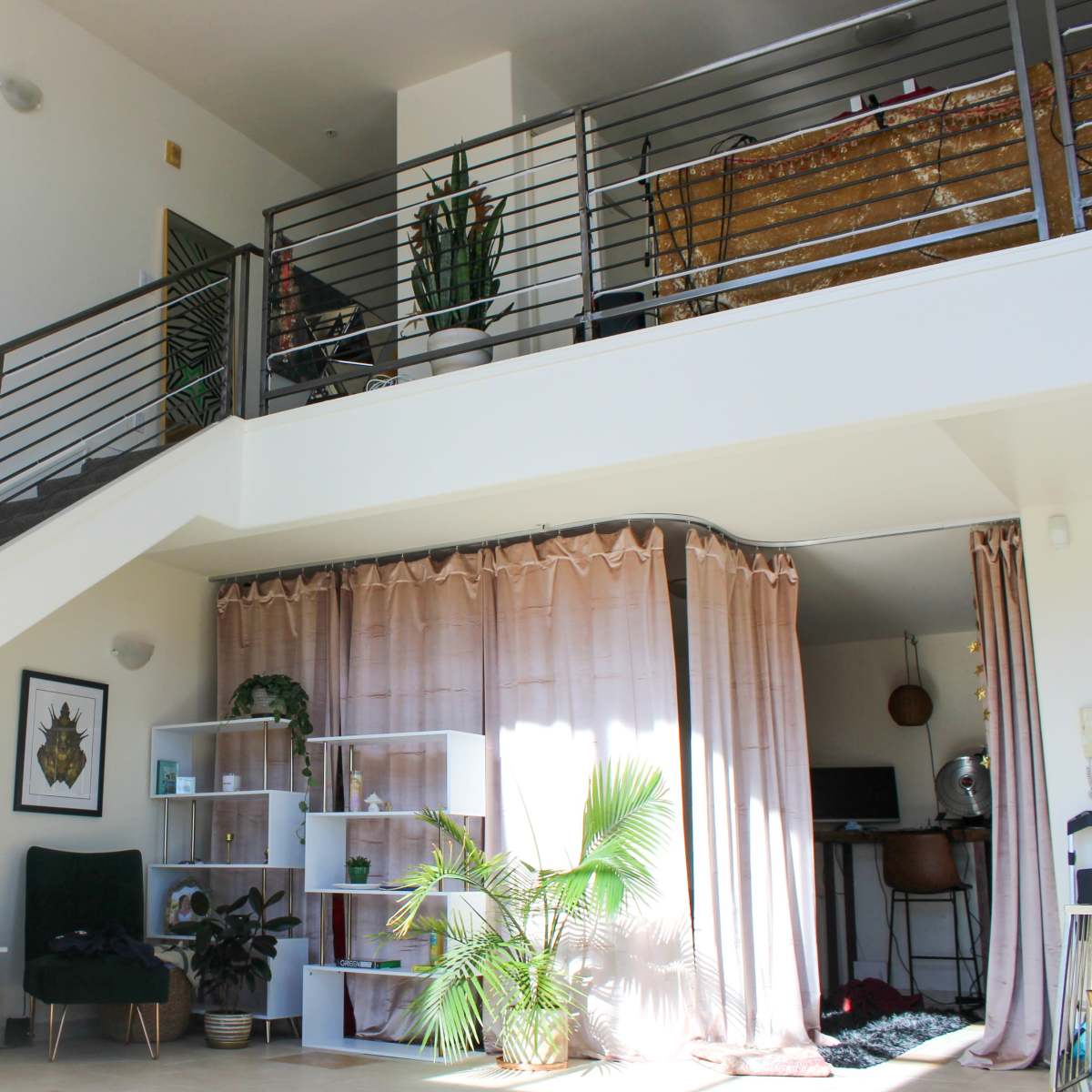 A two-level living space with a staircase, plants, and a blend of modern furniture and decorative elements.