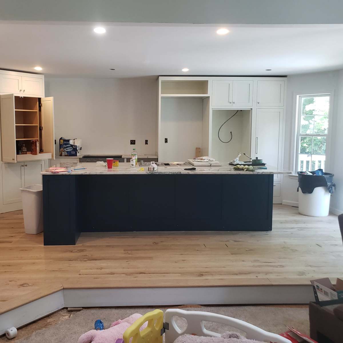 A spacious kitchen with an island, wooden flooring, and unfinished cabinetry.
