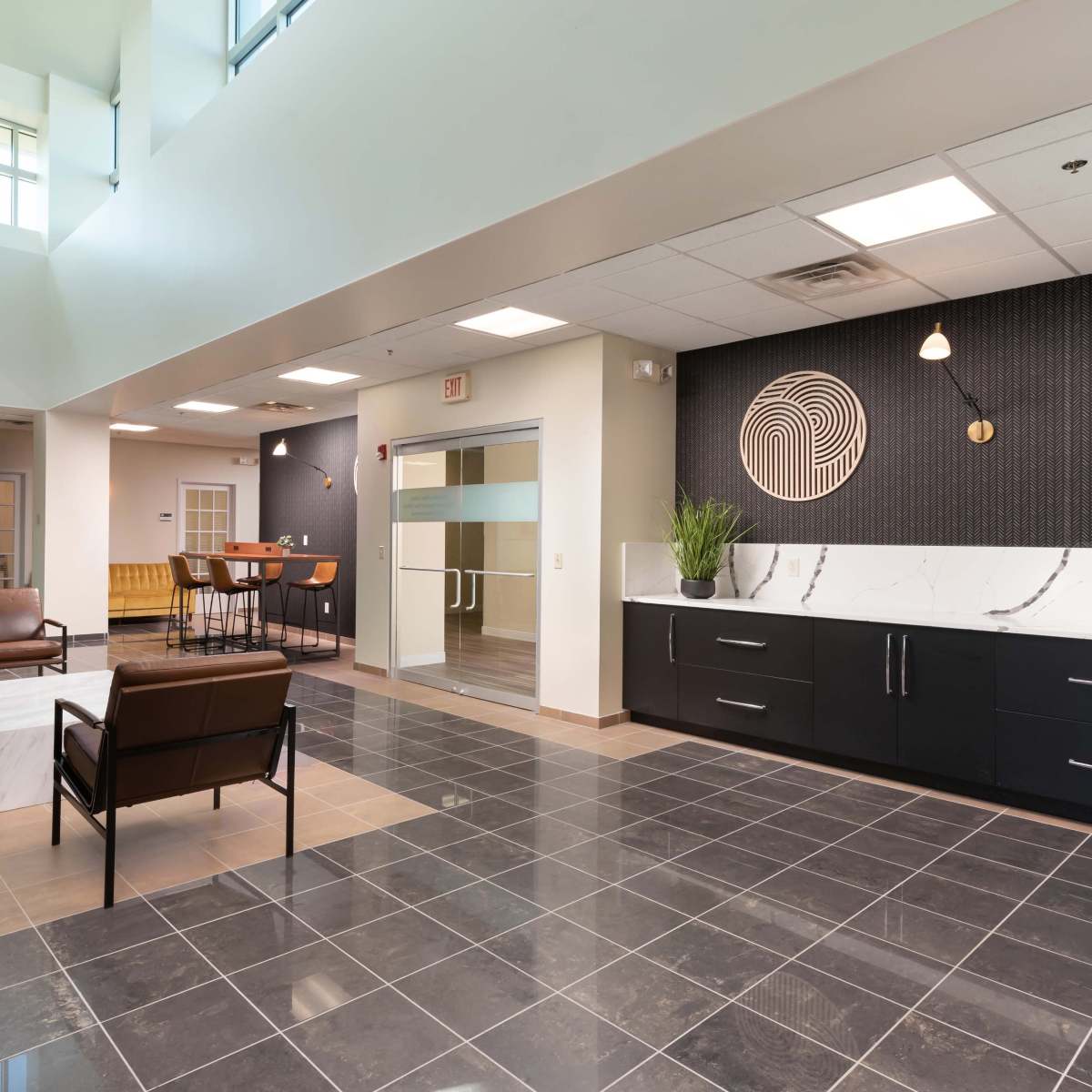 A modern lobby area featuring tiled flooring, contemporary furniture, and a reception area with a textured wall design.