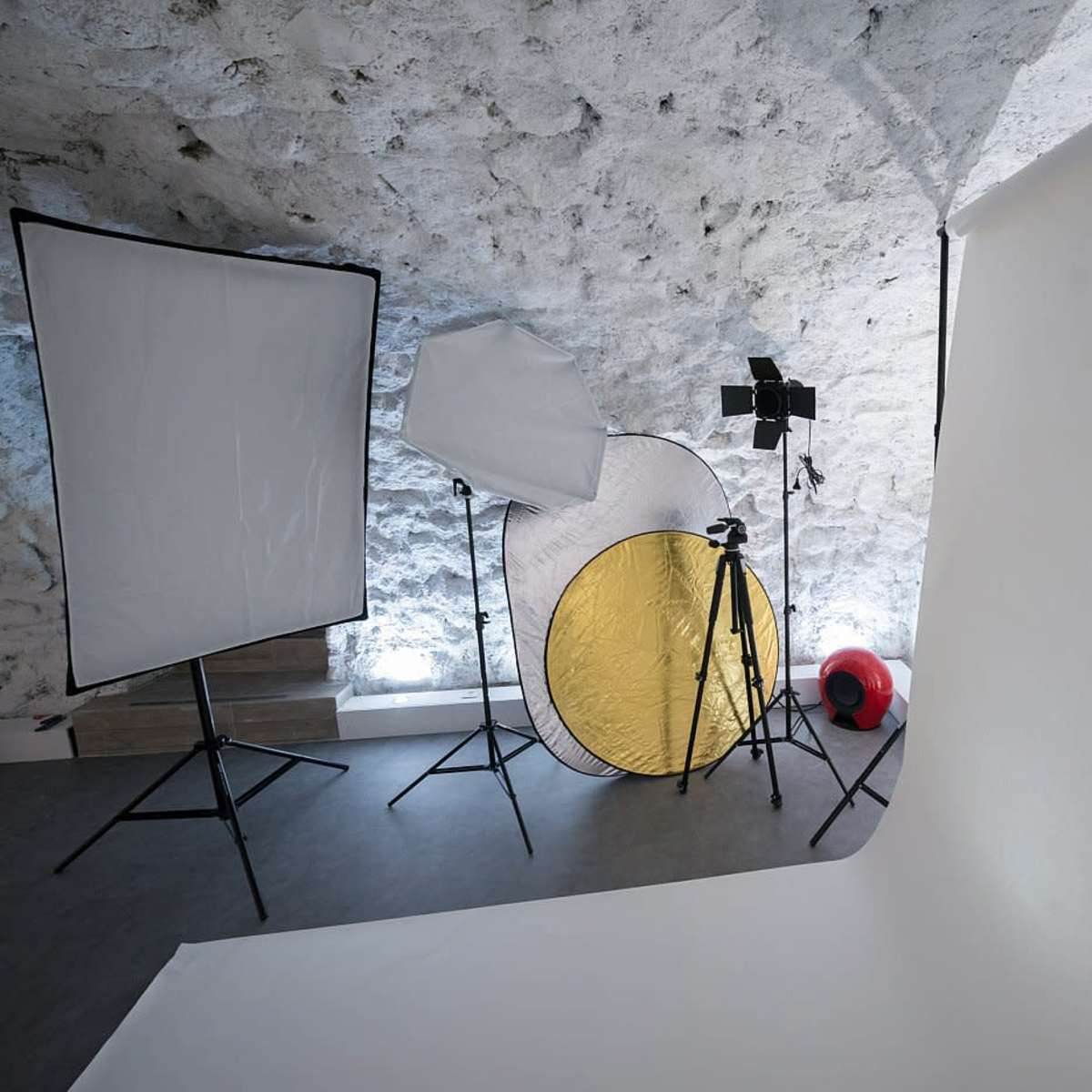 A photography studio setup with multiple light modifiers and a blank backdrop.