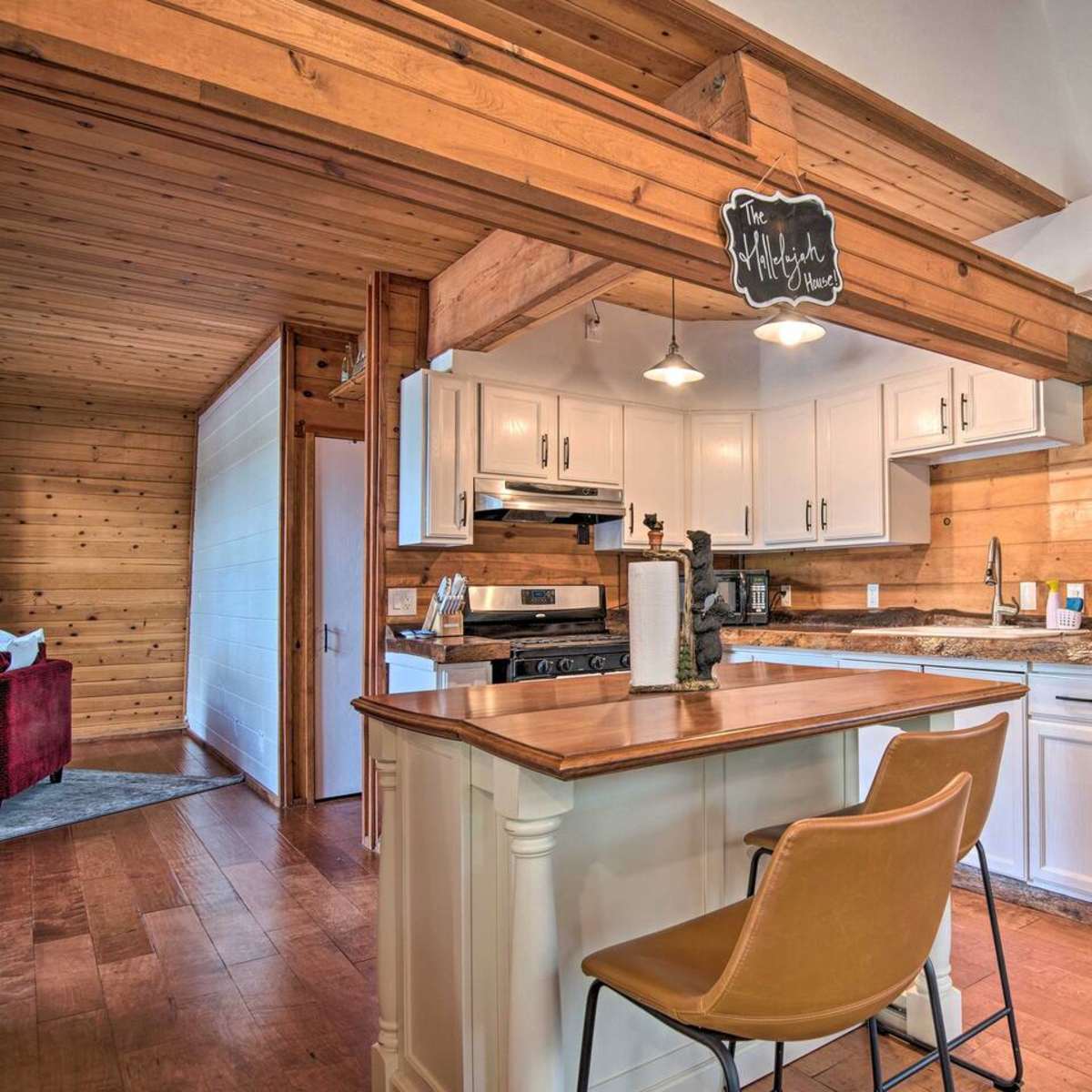 A modern kitchen features white cabinets, a granite countertop, stainless steel appliances, and a wooden beam overhead.