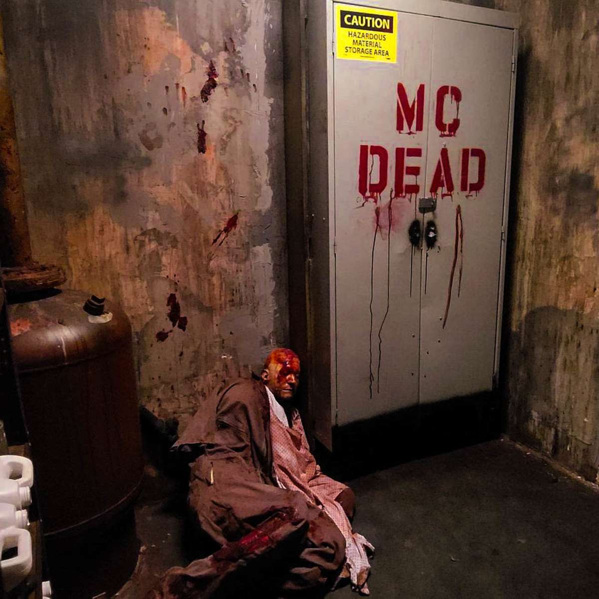 A dimly lit corridor features a door labeled "MC DEAD," with blood splatters on the walls and a figure lying on the ground.