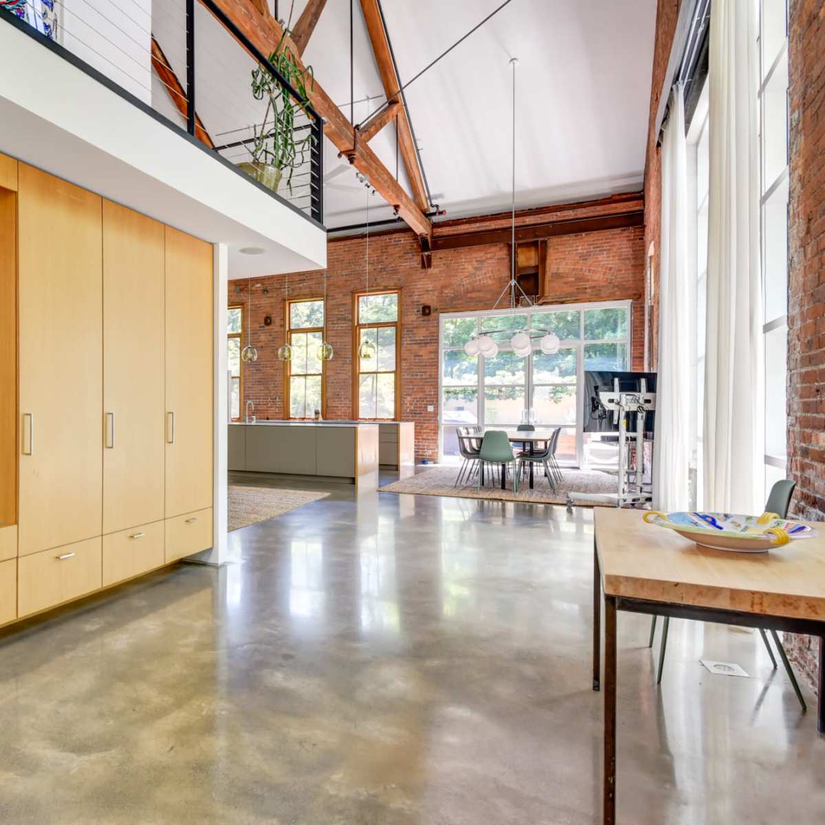 A modern interior space featuring a wooden cabinetry unit, large windows, and an open layout connecting to a dining area.