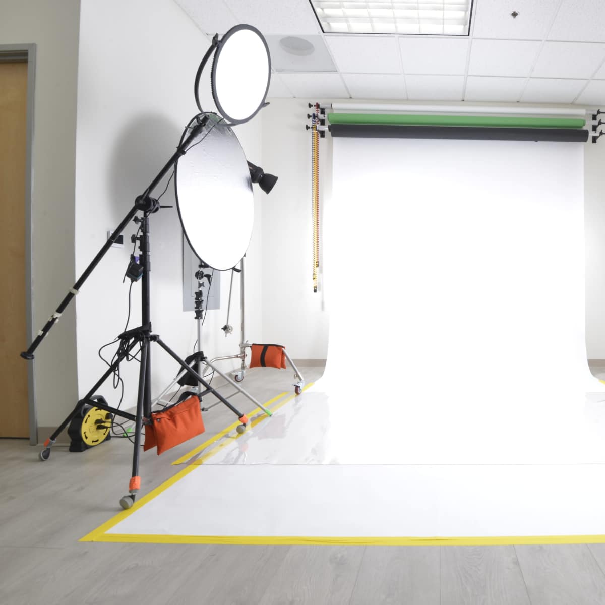 A photography studio with a white backdrop, multiple lighting equipment, and reflectors set up for a shoot.