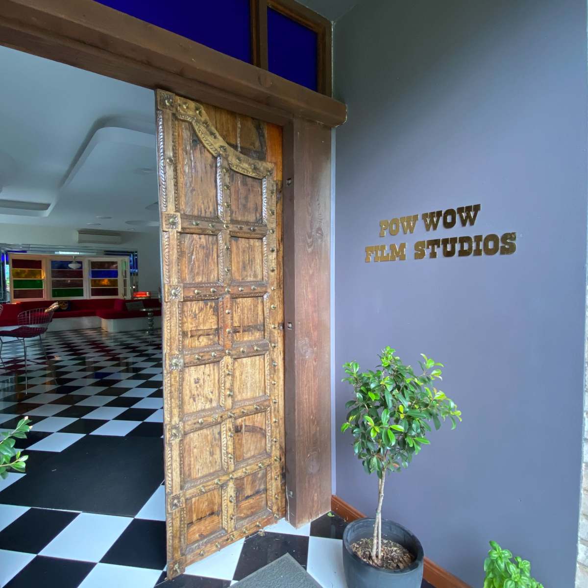 The entrance to Pow Wow Film Studios features a rustic wooden door open to reveal a black and white checkered floor inside.