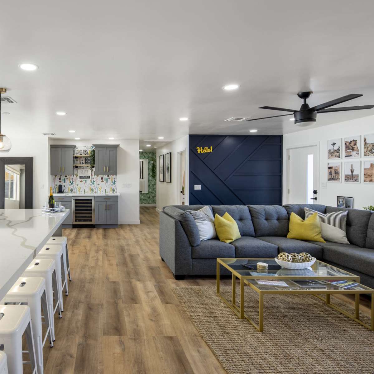 A modern open-concept living area featuring a spacious kitchen island with seating, a cozy sectional sofa, and decorative elements on the walls.