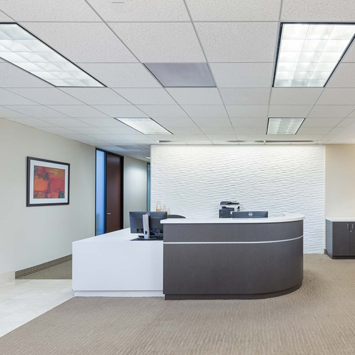 A modern office reception area featuring a front desk, seating, and muted lighting.