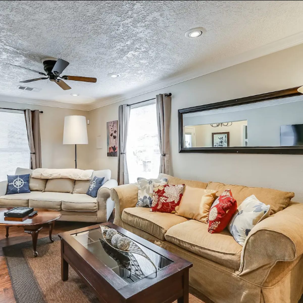 A living room furnished with two sofas, a coffee table, a lamp, and framed artwork on the walls.
