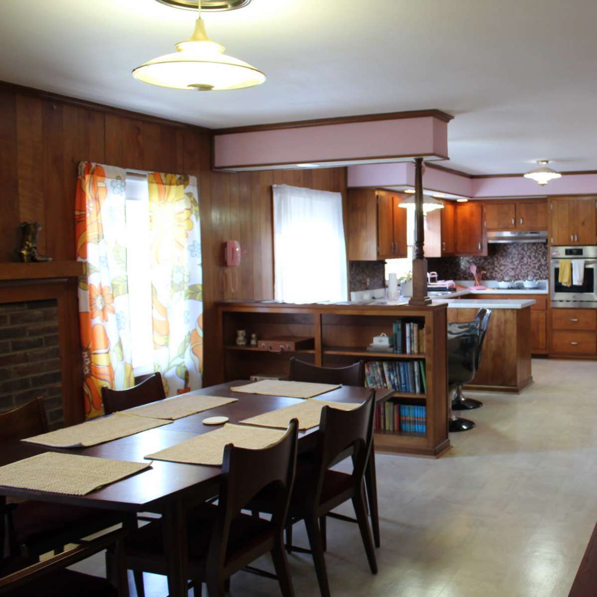 A spacious kitchen and dining area feature wooden paneling, a long table with chairs, and modern appliances.