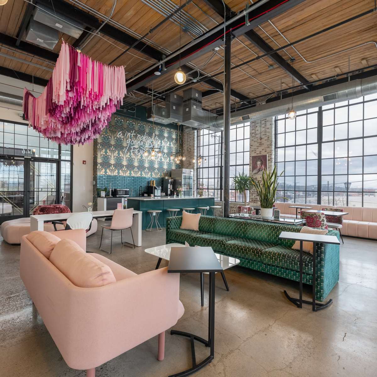 A modern cafe with colorful seating, large windows, and a striking artwork installation hanging from the ceiling.