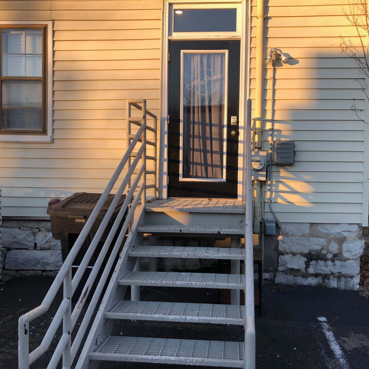 A metal staircase leads up to a door on a yellow wooden building.