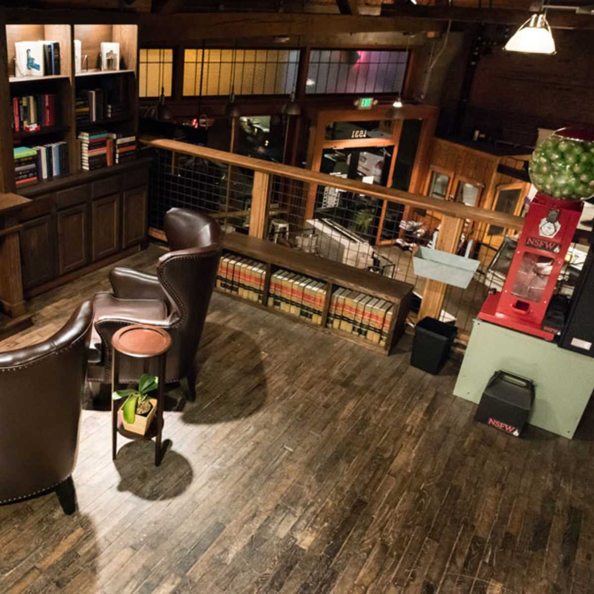 A cozy reading nook with two leather chairs facing each other, surrounded by wooden bookshelves, and overlooking a spacious interior with wooden flooring and additional seating areas.