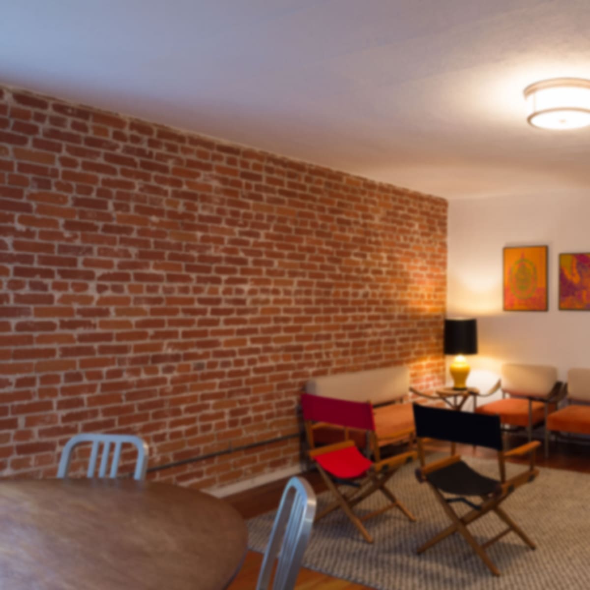 A well-lit living space featuring a brick wall, various seating options, and a round dining table.