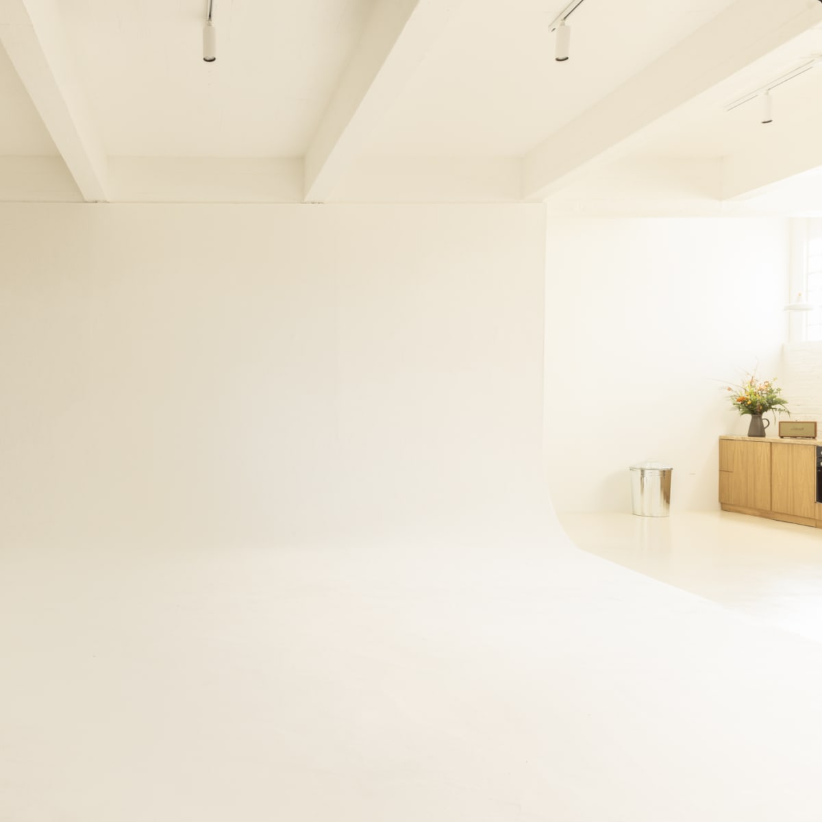 A minimalist photography studio with a large white backdrop and light-colored flooring.