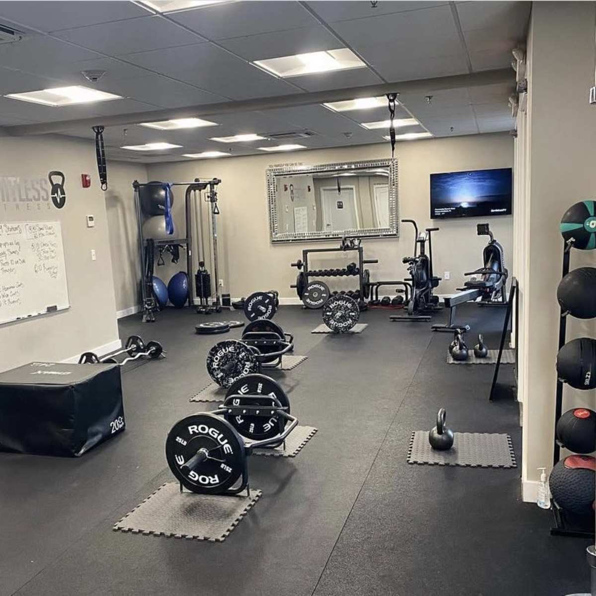 A well-equipped gym with various weightlifting and exercise equipment arranged across a carpeted floor.