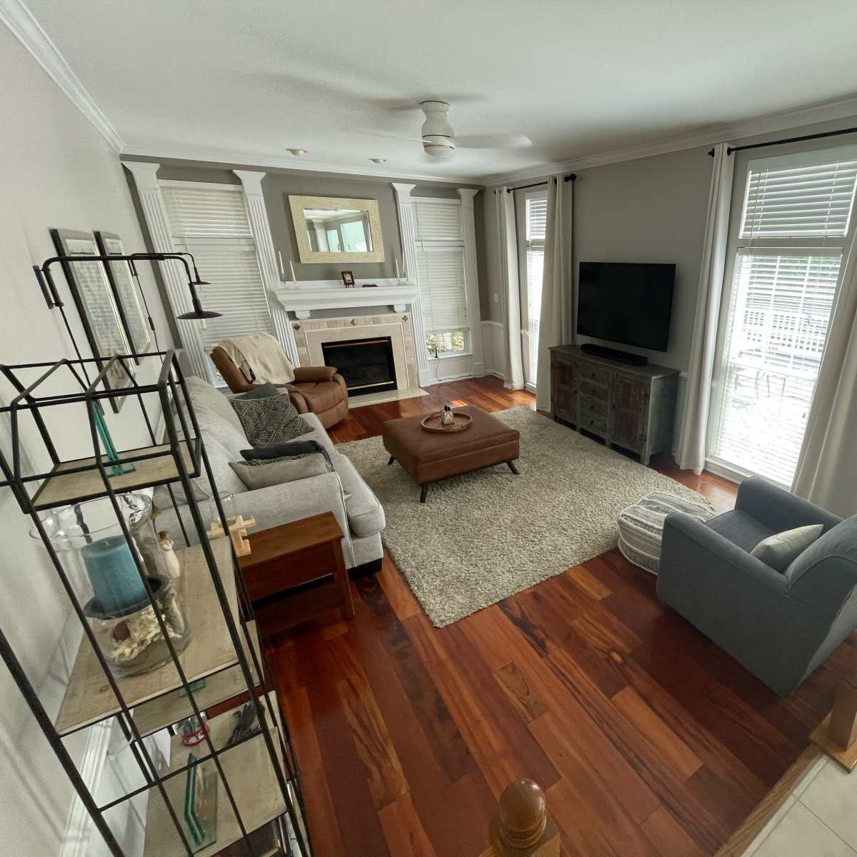 A well-furnished living room with a fireplace, a television, and a mix of seating arrangements, including a sofa and an armchair.