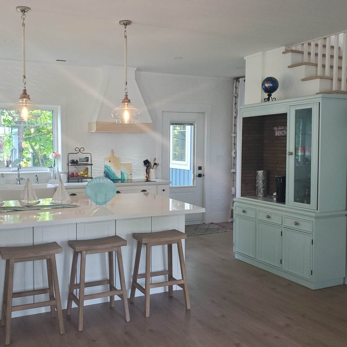 A modern kitchen equipped with a large island, barstools, and a mix of wood and white cabinetry.