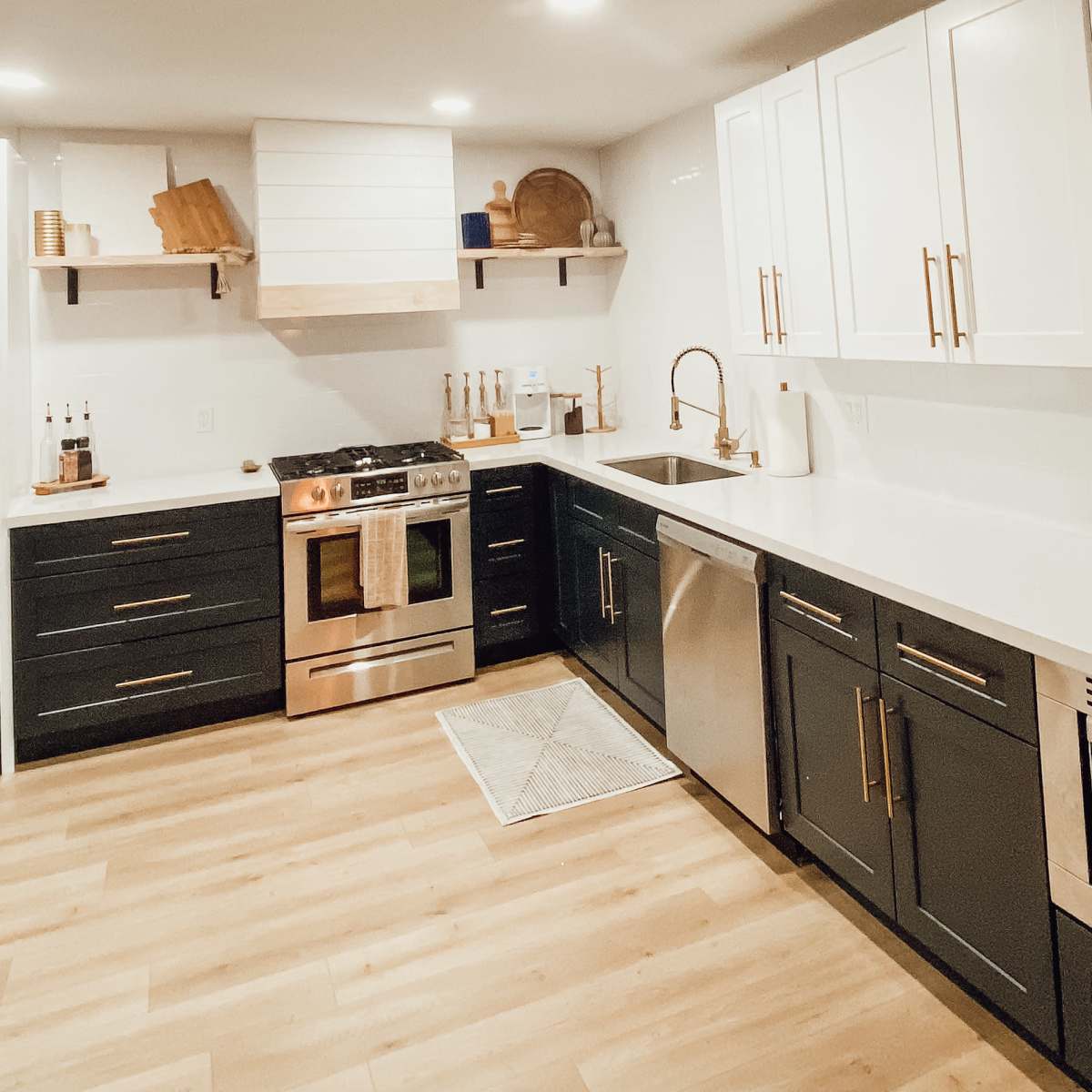 A modern kitchen features stainless steel appliances, white cabinetry, and gray countertops with a wooden accent decor.