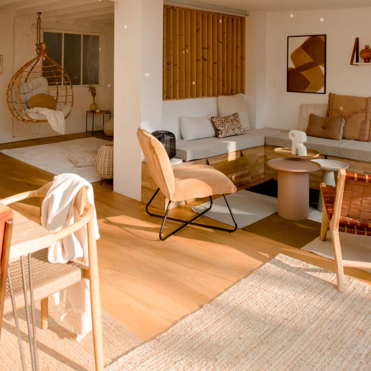 A bright, modern living space with a sectional sofa, a small coffee table, a wooden dining table, and large windows allowing natural light to illuminate the room.