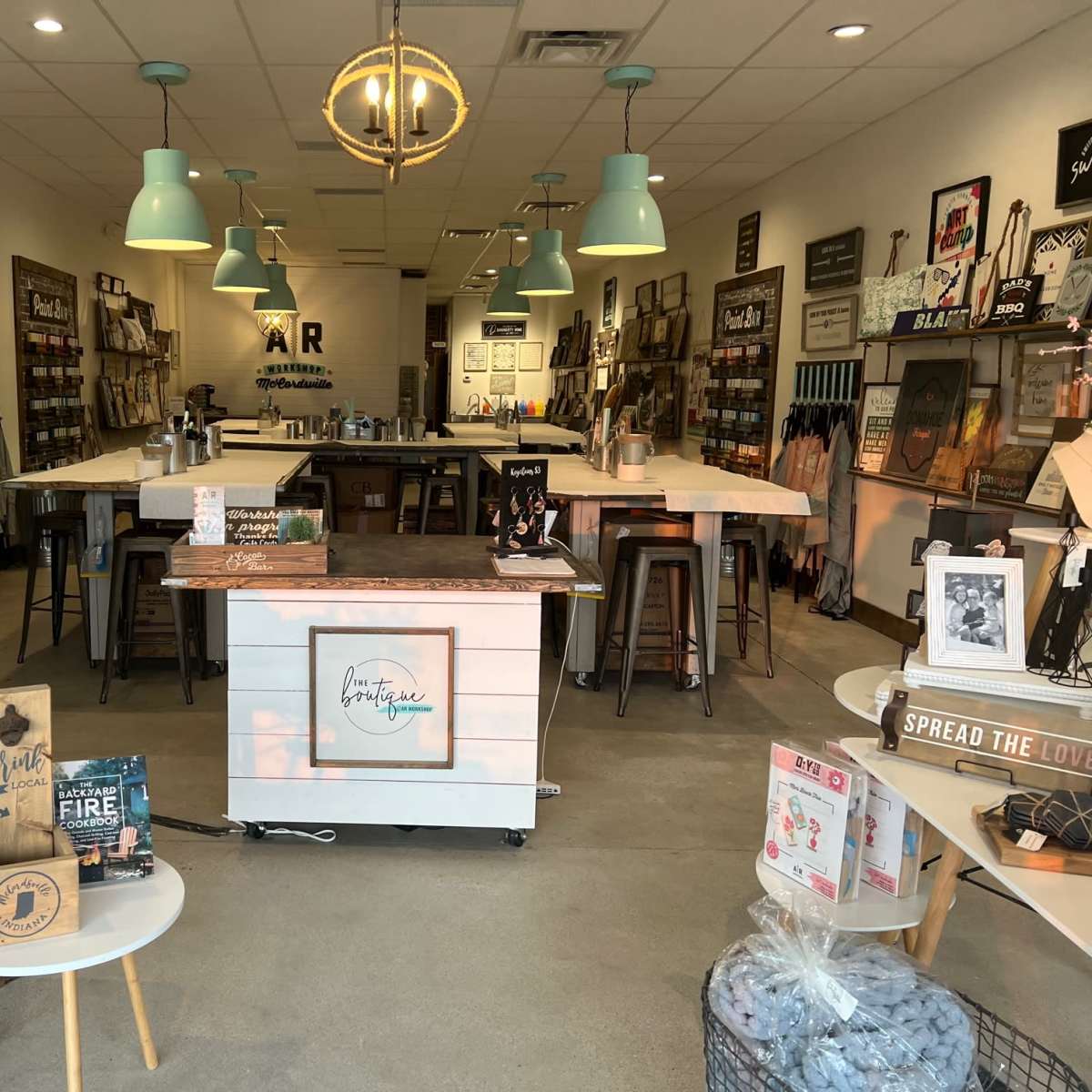 An interior of a retail space featuring wooden display tables, wall art, and shelves filled with various decorative items.