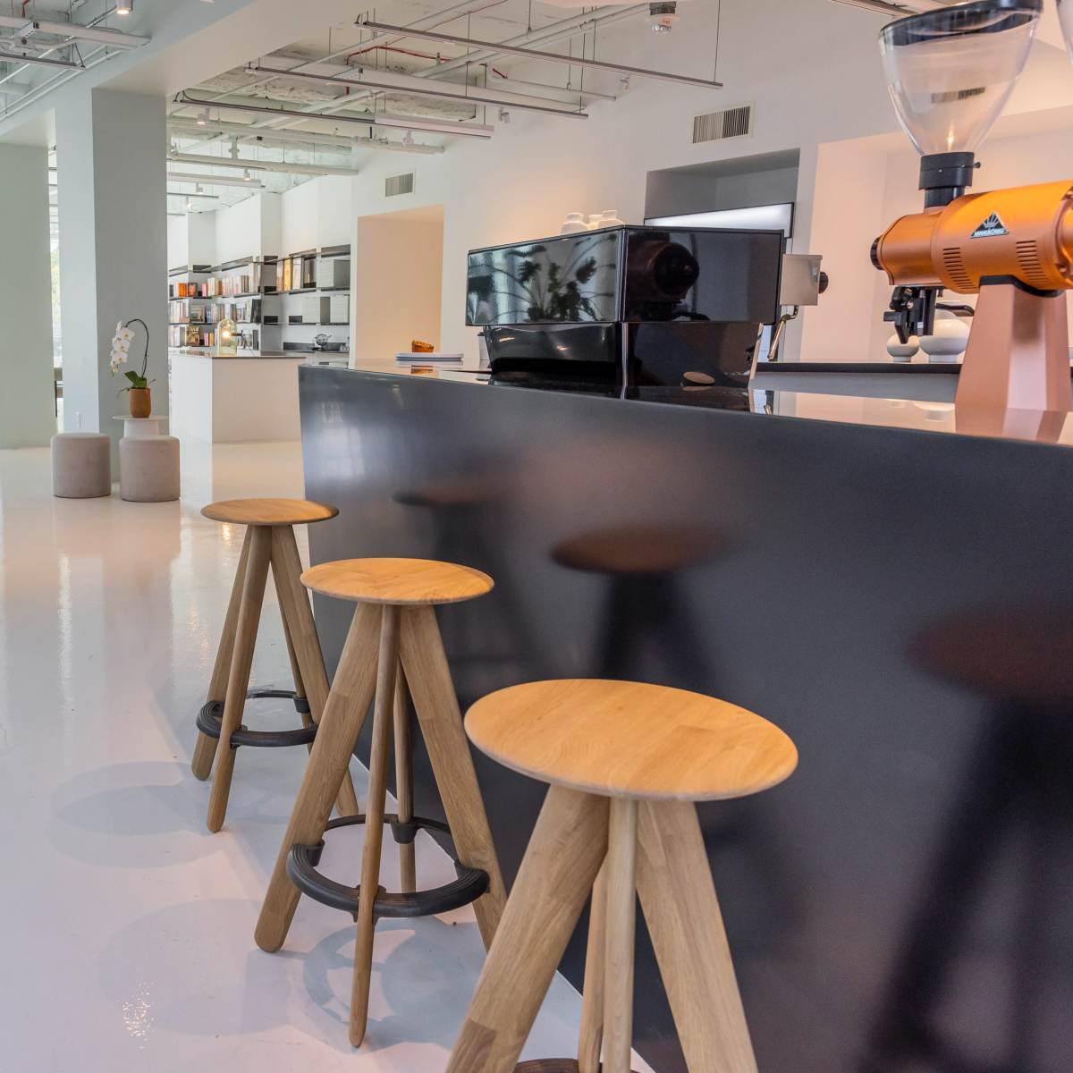 A modern interior space with minimalistic design, featuring a sleek counter, wooden stools, and various decorative elements.