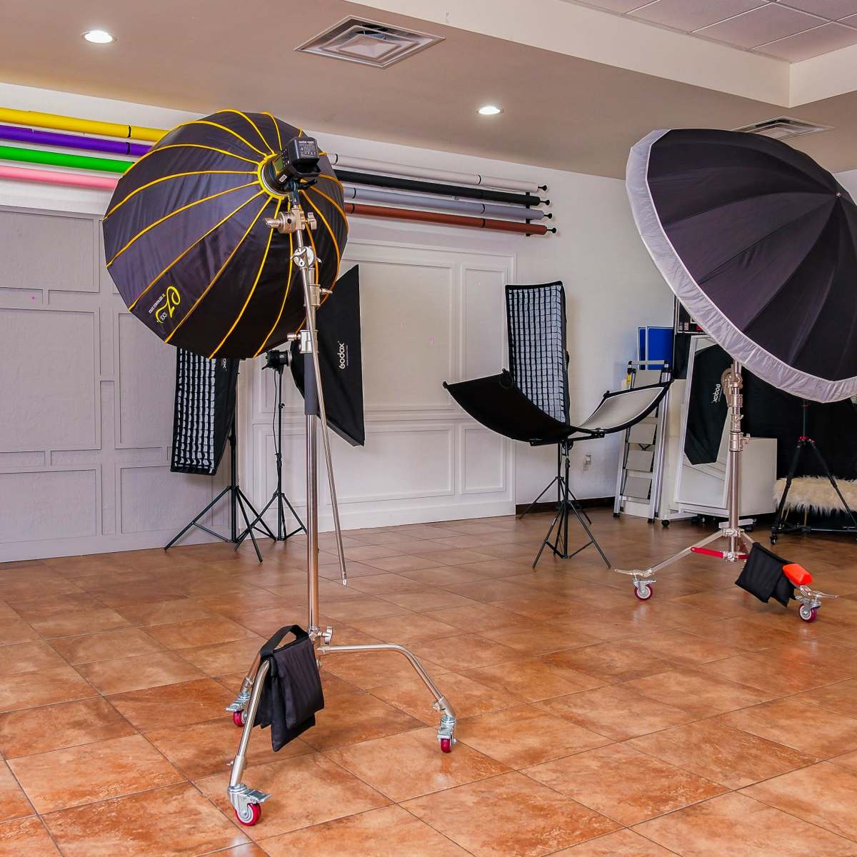 A photography studio equipped with various lighting setups, backdrop stands, and props arranged in a spacious interior.
