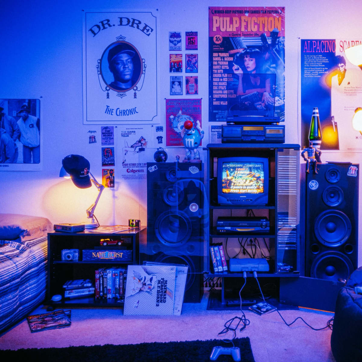 A colorful room with a bed, a TV stand featuring a classic television and speakers, and various movie posters and memorabilia on the walls.