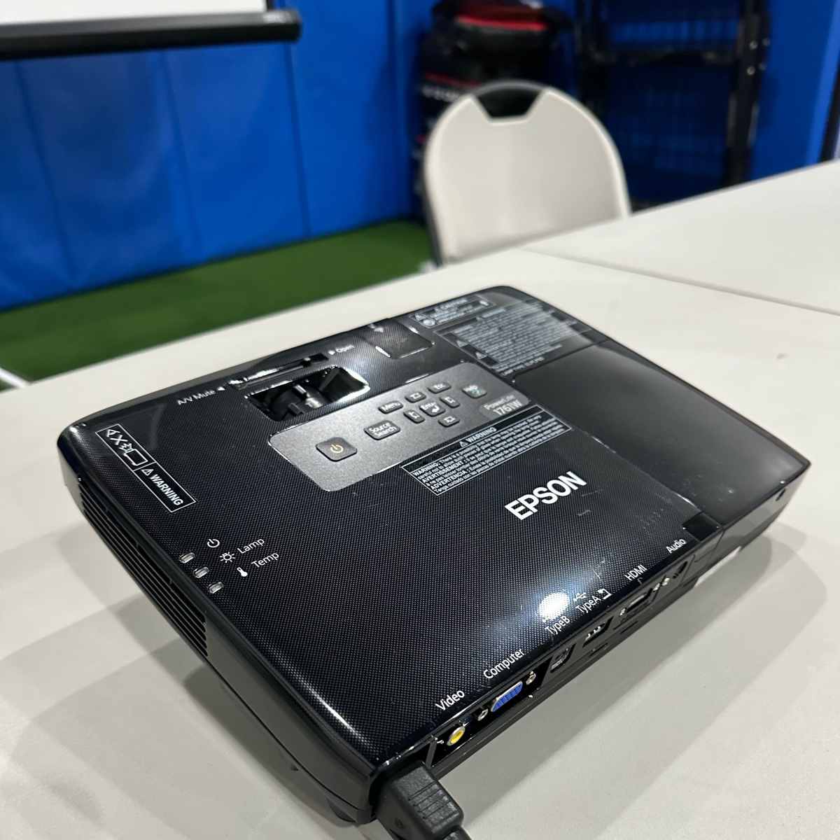An Epson projector placed on a table, connected by a cable.