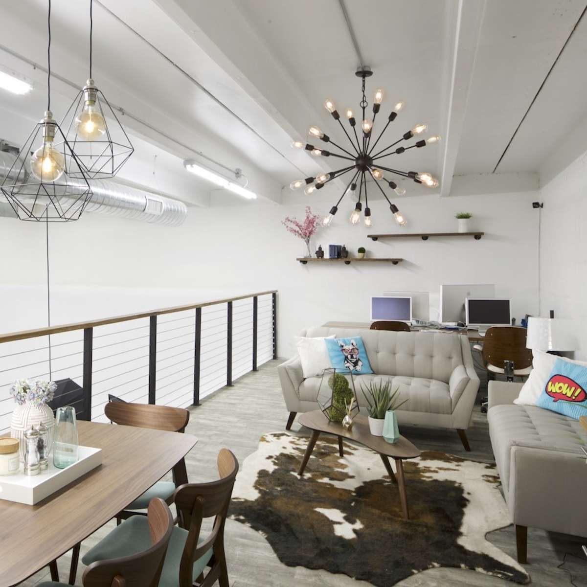 A modern loft-style interior with a dining table, a decorative sofa arrangement, and industrial lighting fixtures.