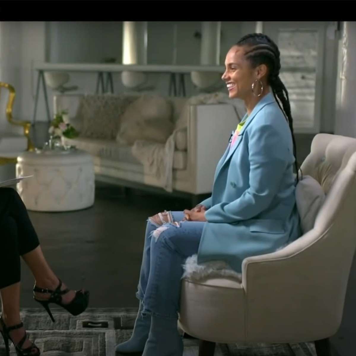 Two women sit facing each other in a modern, well-lit room with stylish furniture, engaged in an interview.