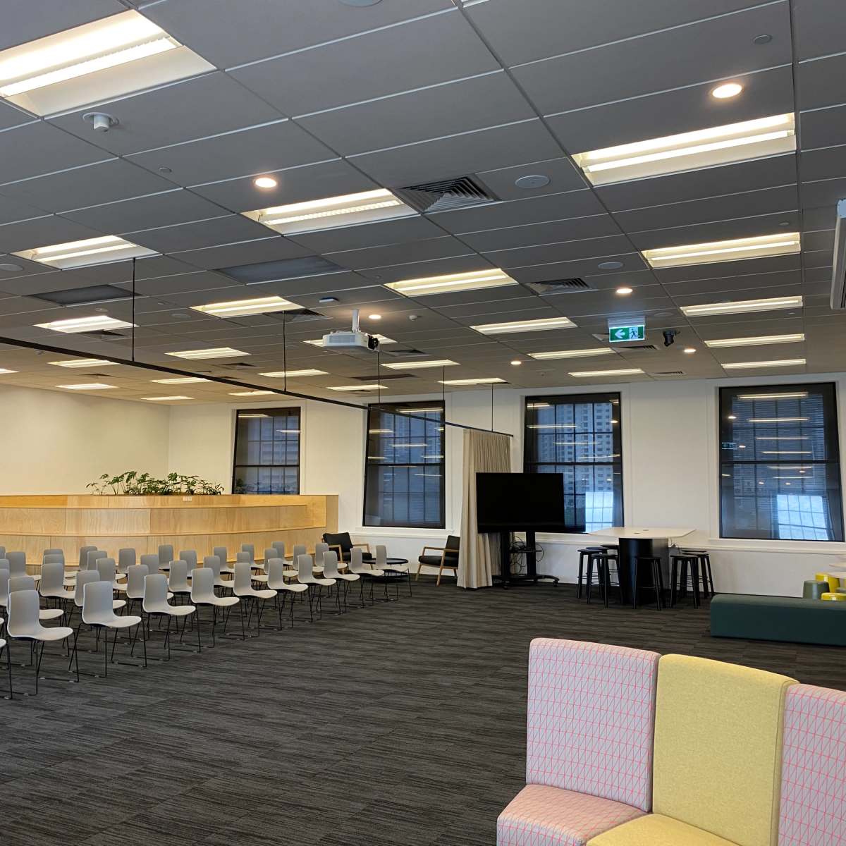 An open office space with rows of chairs arranged for an event, a reception area with a wooden counter, and various seating options including a couch and tables.